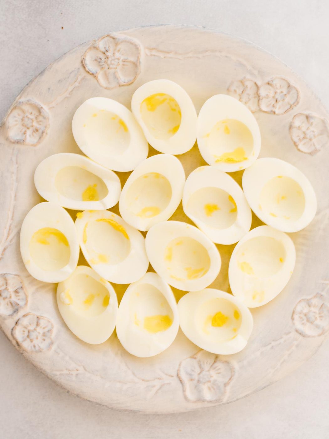 Hard boiled egg whites cut in half, with the egg yolk removed, sitting on a serving platter.
