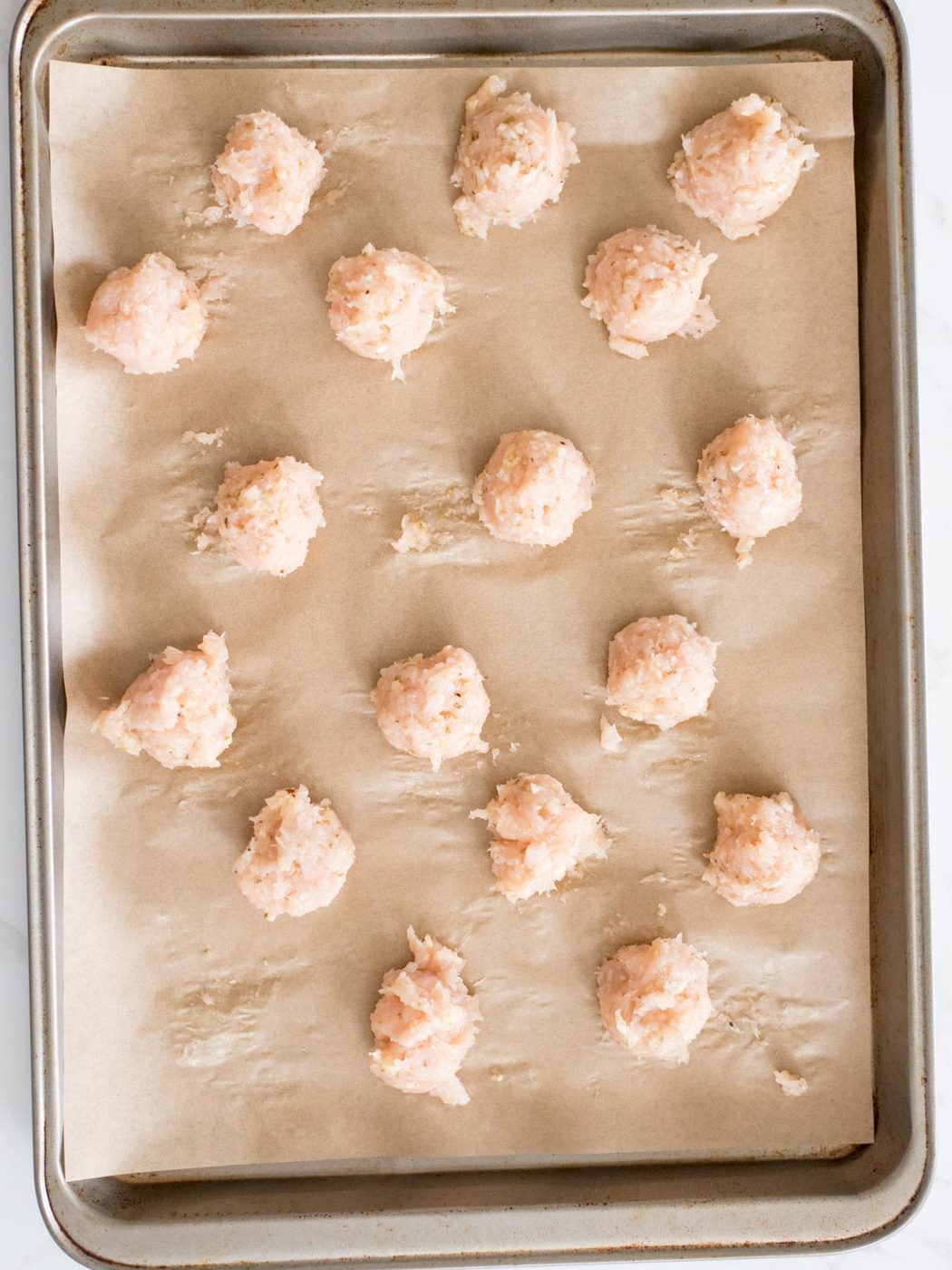 chicken meatballs on a parchment lined sheet pan