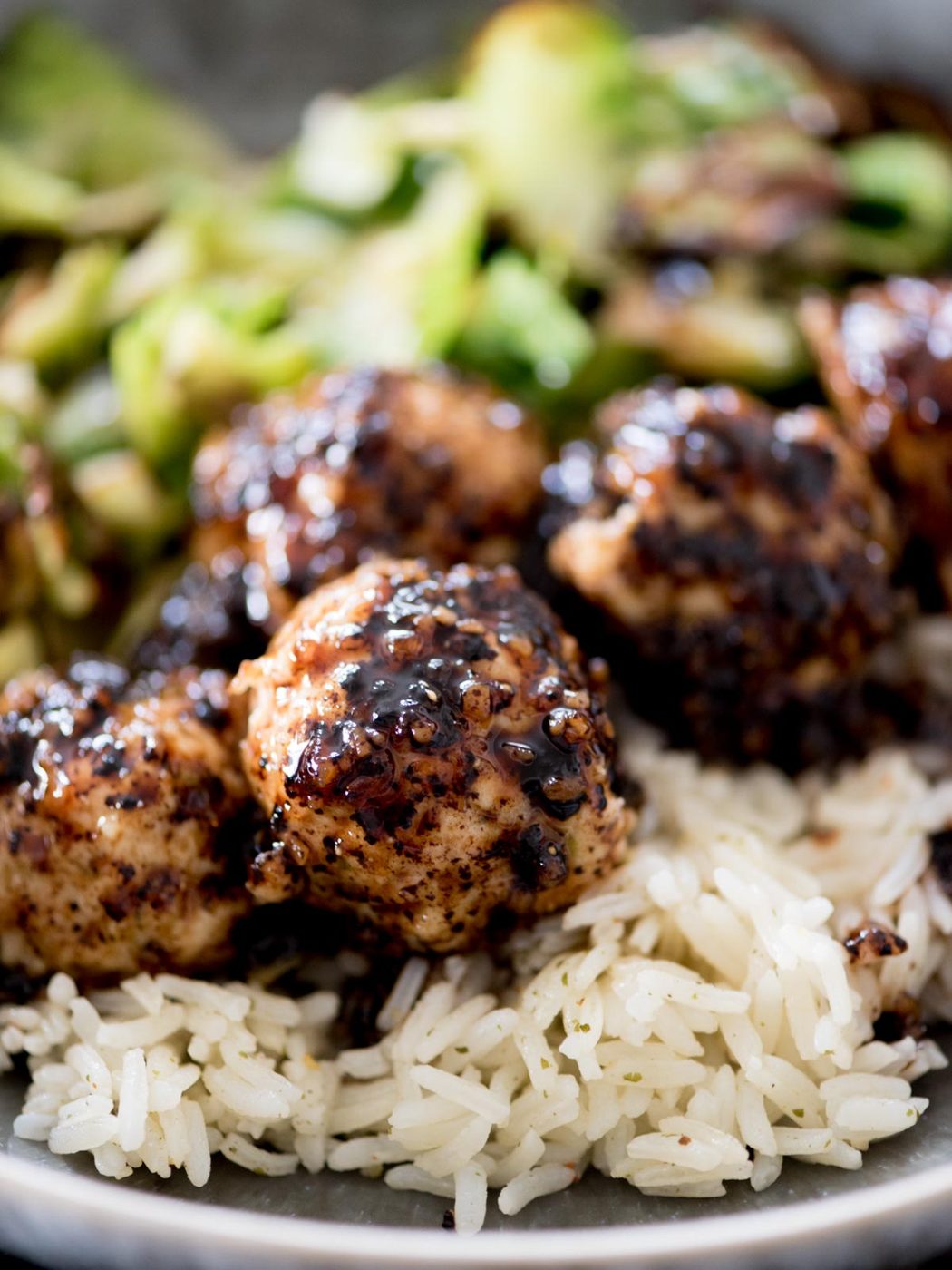sticky sweet chicken meatballs in a bowl with rice and brussels sprouts