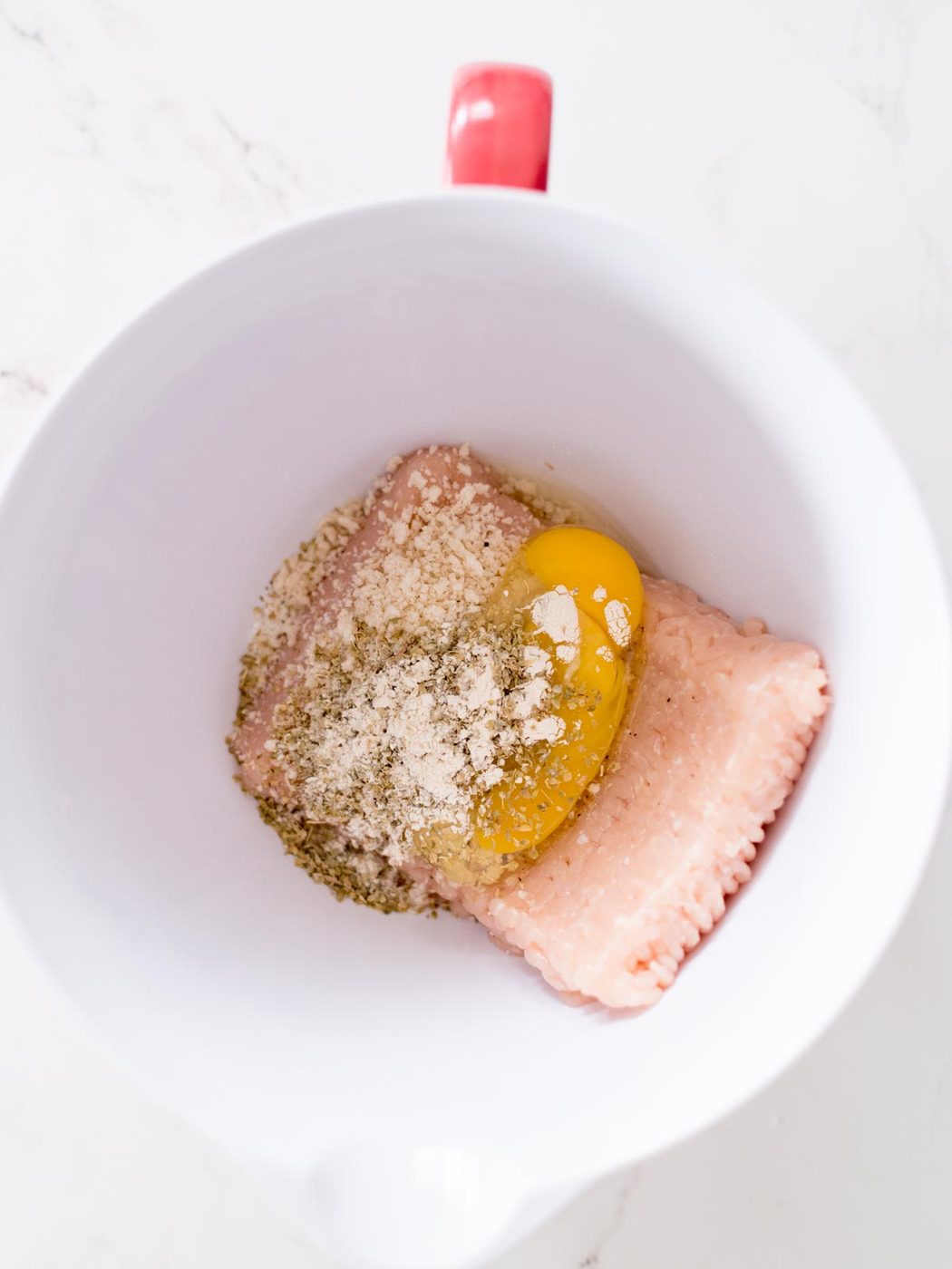 all ingredients for chicken meatballs in a bowl, unmixed