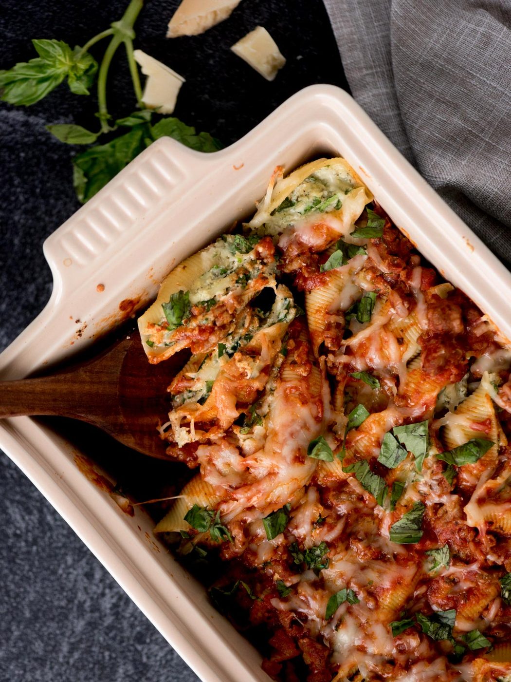 stuffed shells with meat sauce in a baking dish being scooped out