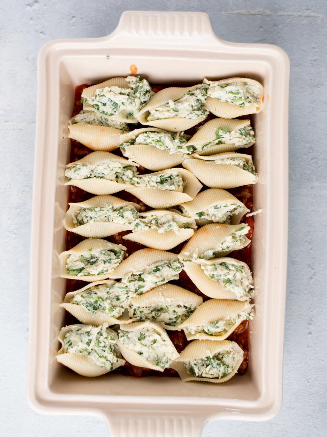 filled shells on the meat sauce in a baking dish
