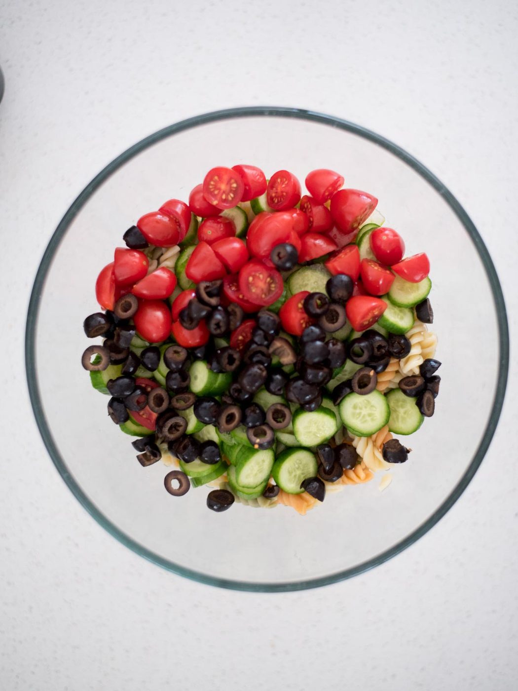 olives added to mixing bowl with vegetables and cooked pasta