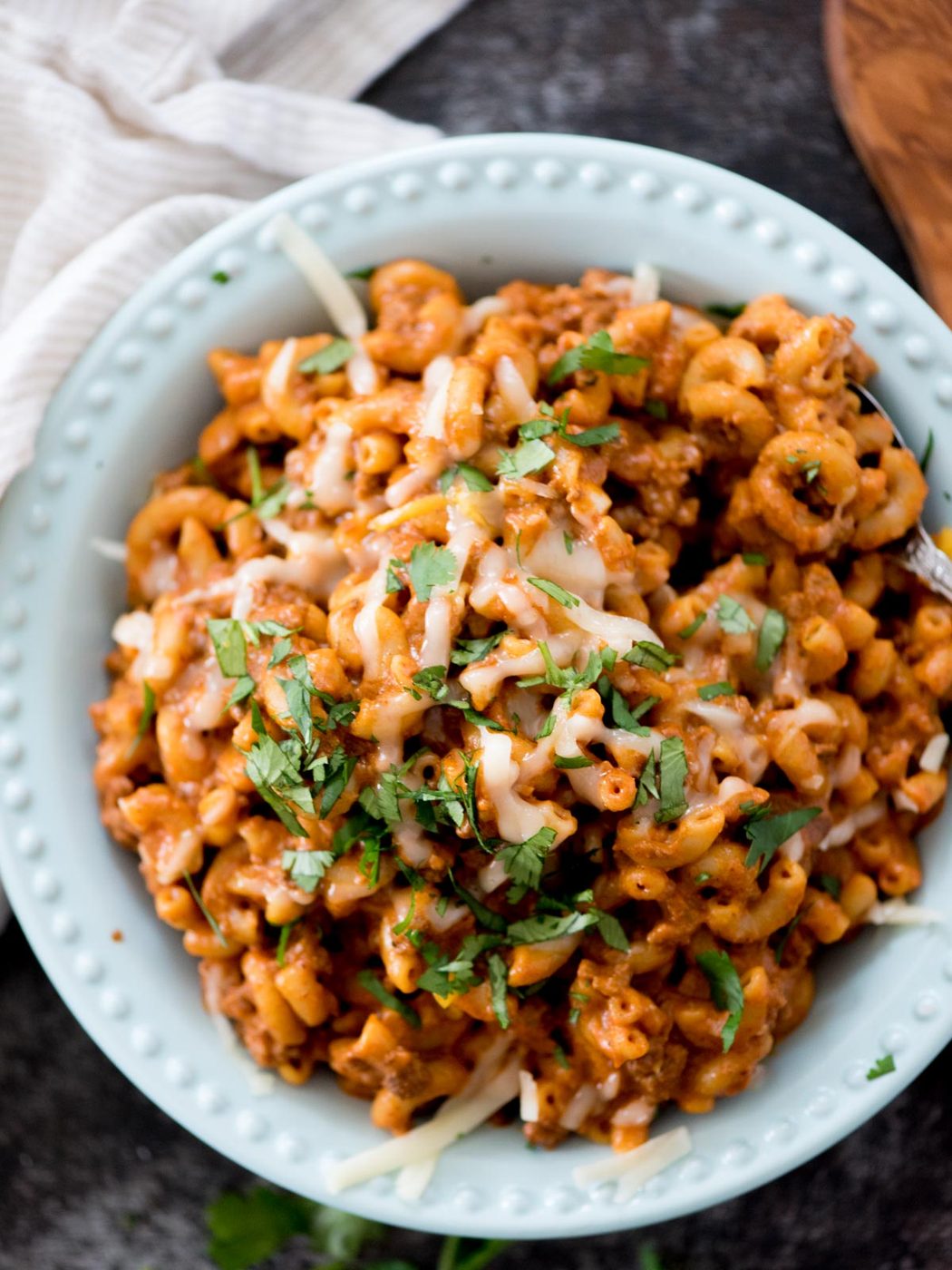 one pot cheesy taco pasta in a blue bowl topped with cheese and cilantro