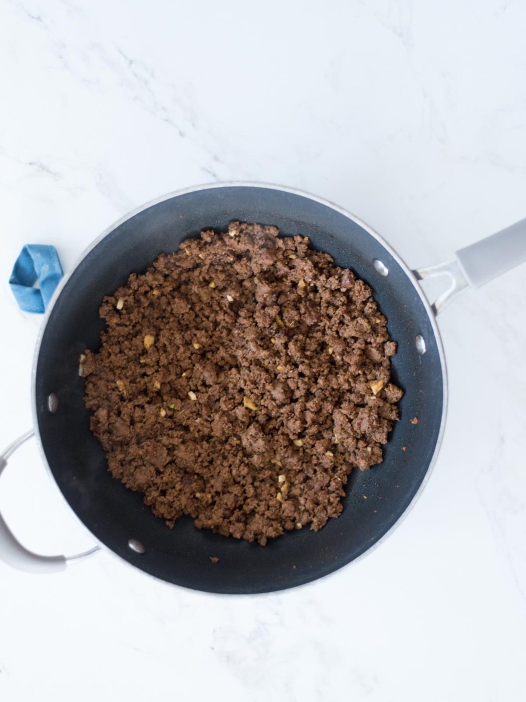 cooked ground beef in a skillet with taco seasoning, onion powder, and garlic