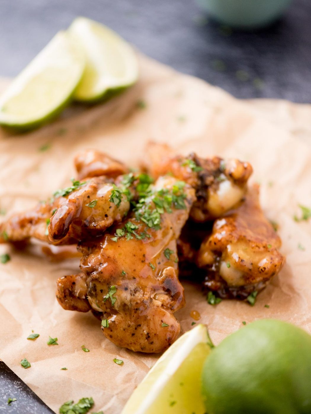 Lime wedges on parchment paper next to tequila lime wings.