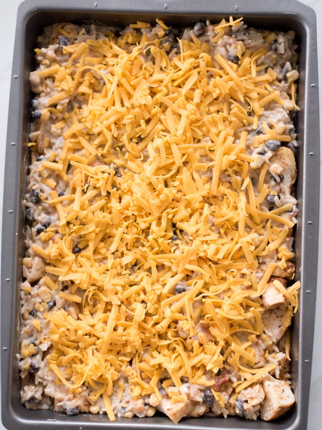 Shredded cheese over the rice mixture in a baking dish.