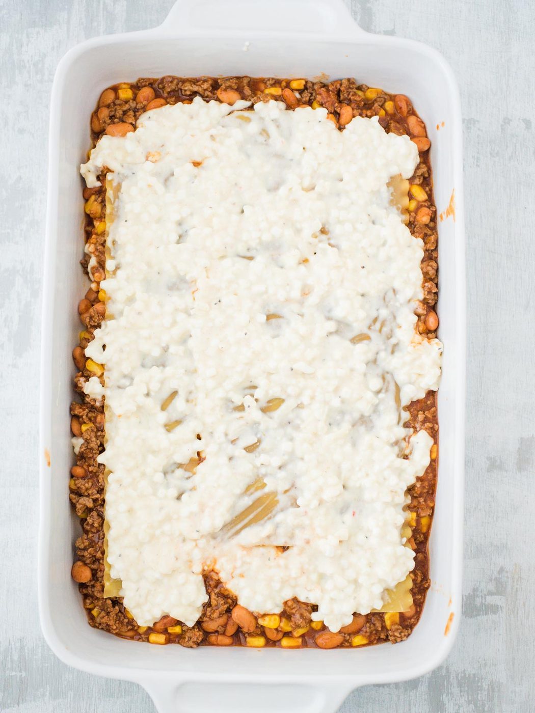 cheese mix layer of tex mex lasagna in a casserole dish