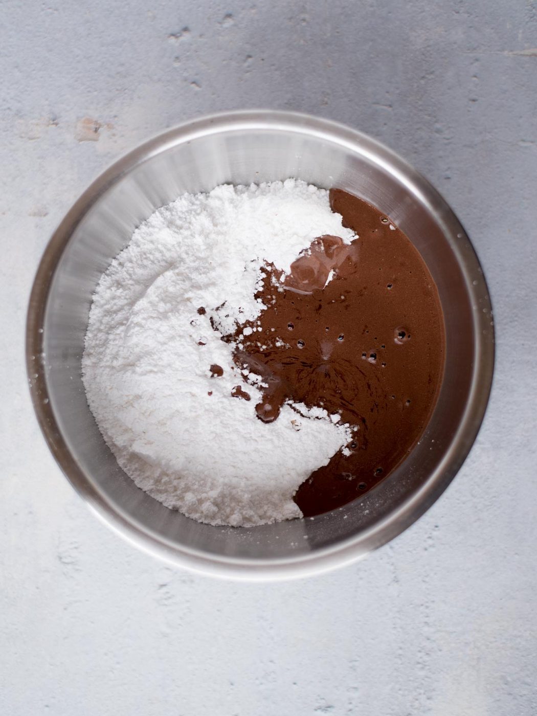 Powdered sugar mixed with chocolate for texas sheet cake frosting in a mixing bowl