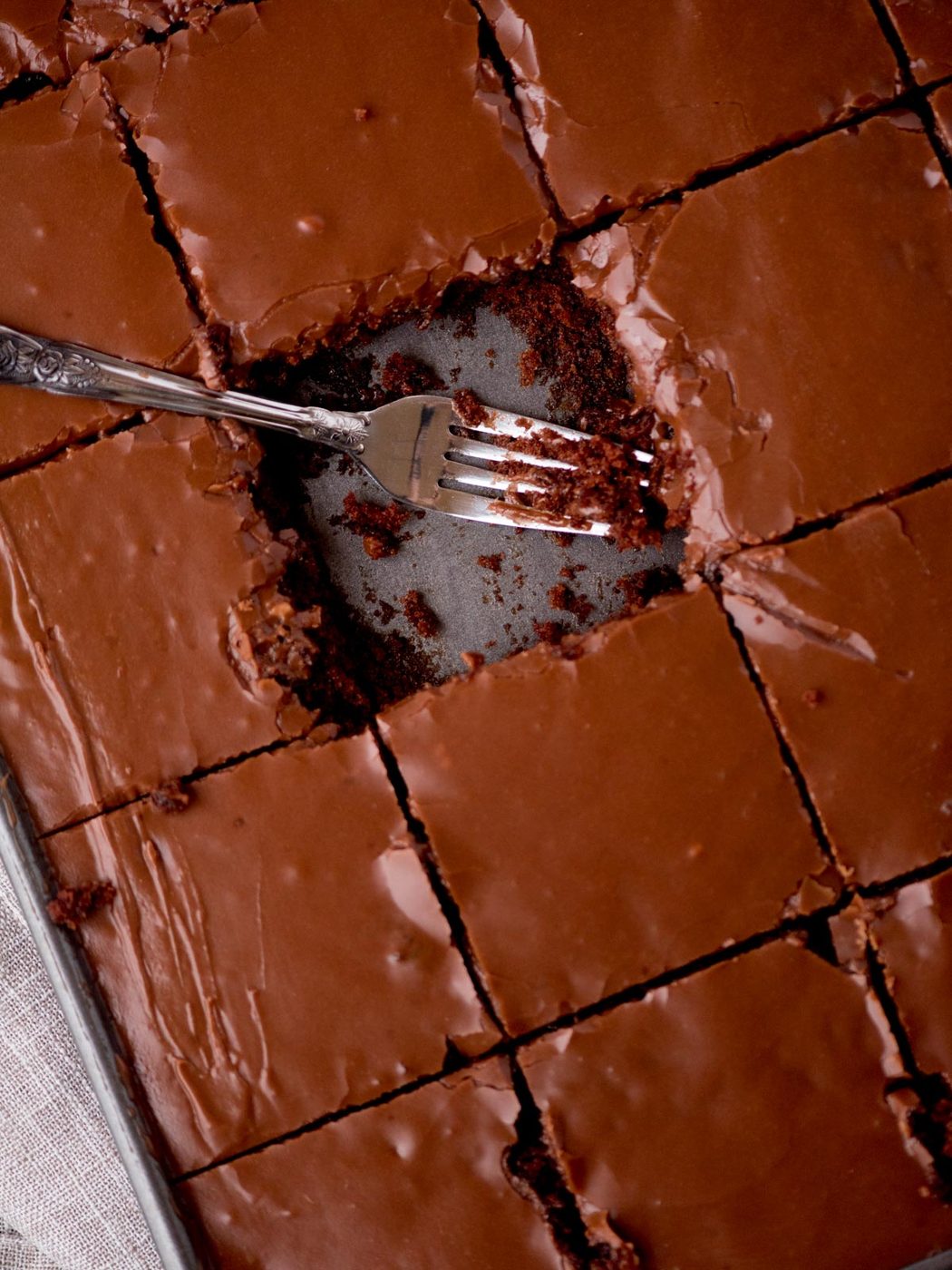 Texas sheet can in a pan with a square cut out and a fork in it. it is surrounded by a kitchen towel