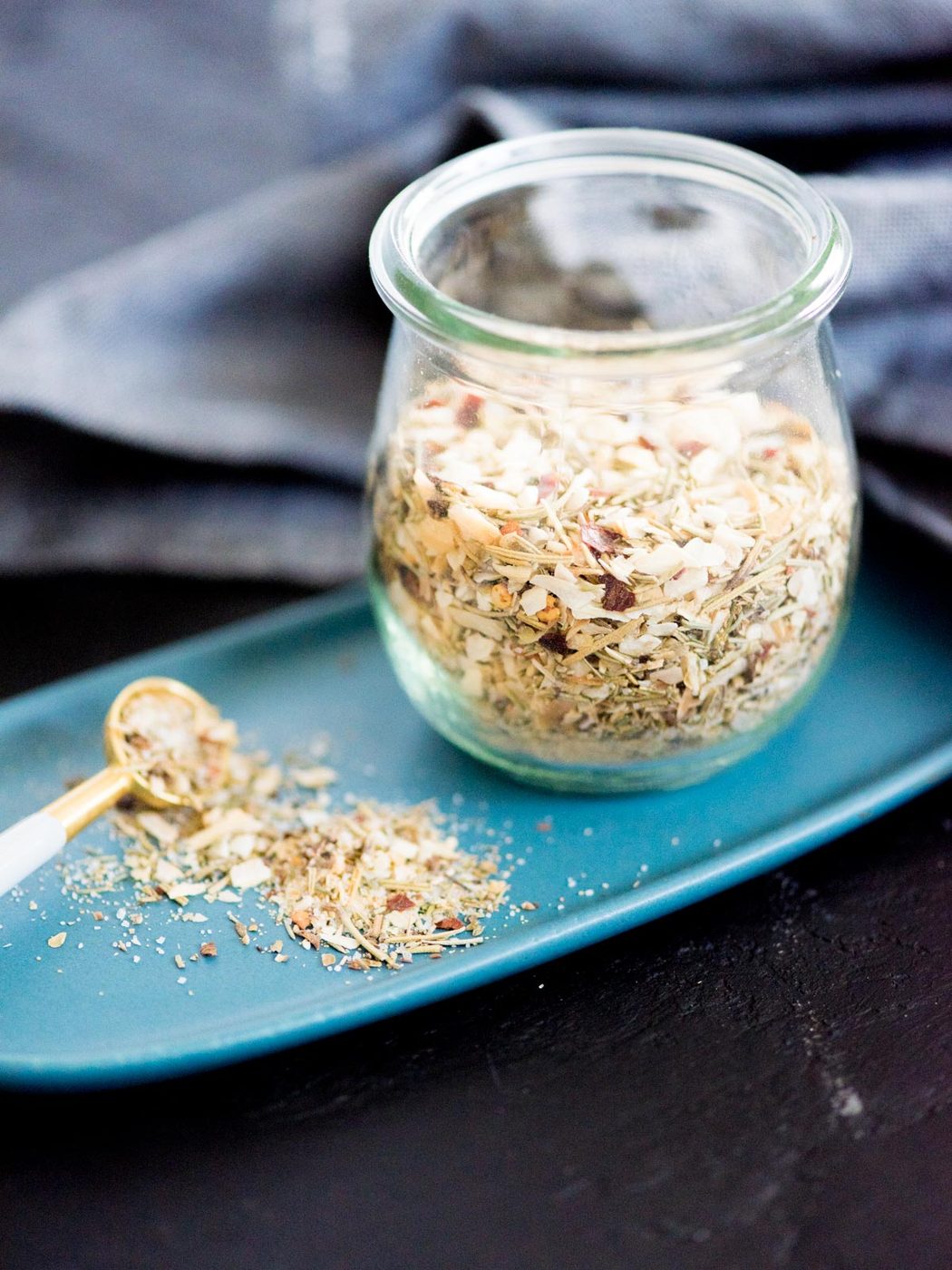 tuscan herb seasoning blend in a jar with a measuring spoon and plate