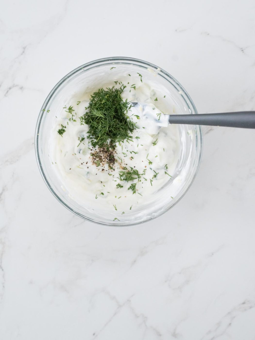 dill, pepper, and salt added to greek yogurt for tzatziki