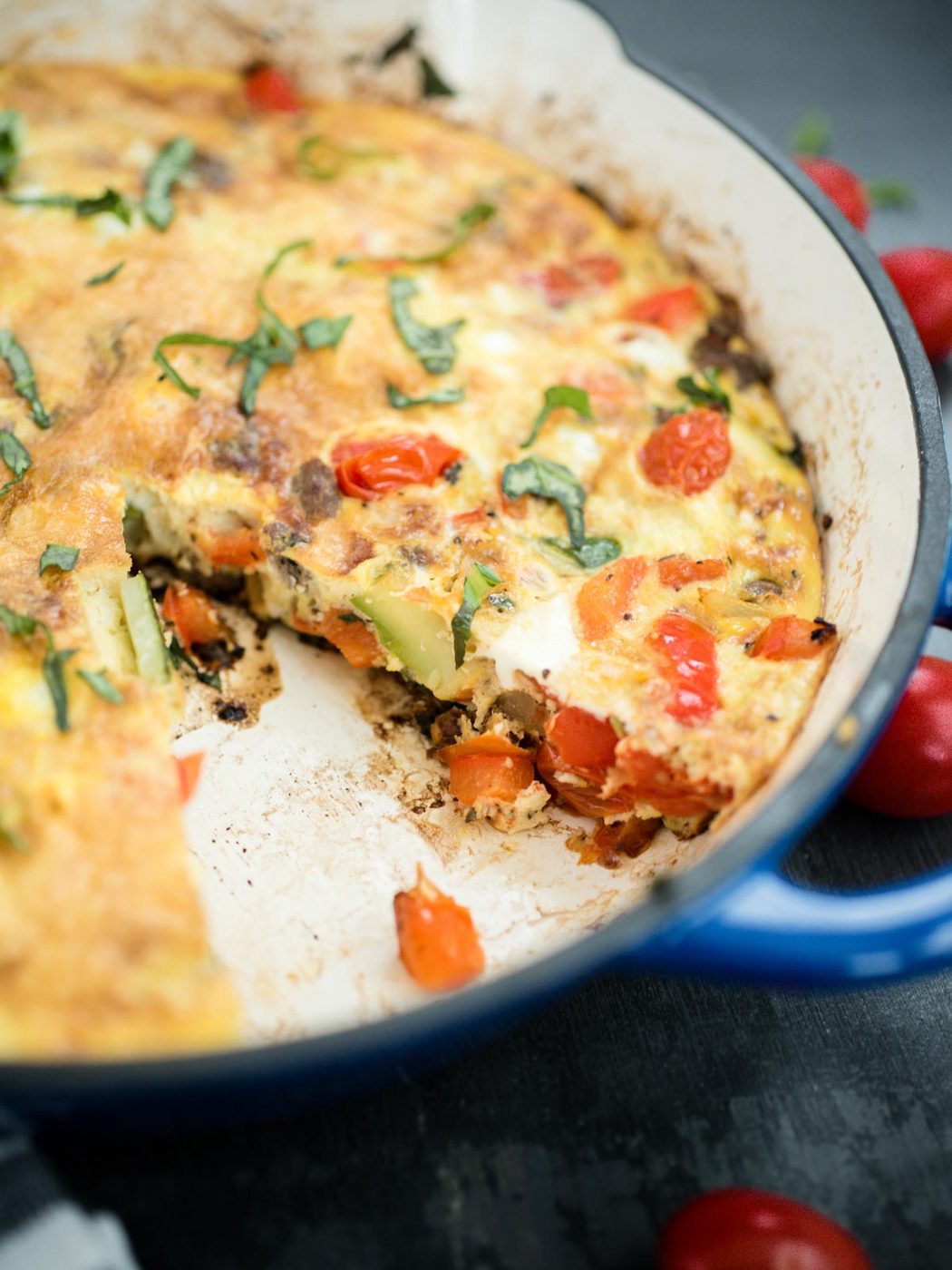 frittata in a cast iron enamel pan with slice removed