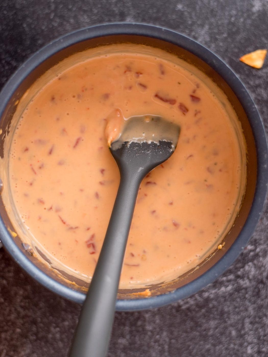 Spatula resting in a saucepan of velveeta queso.