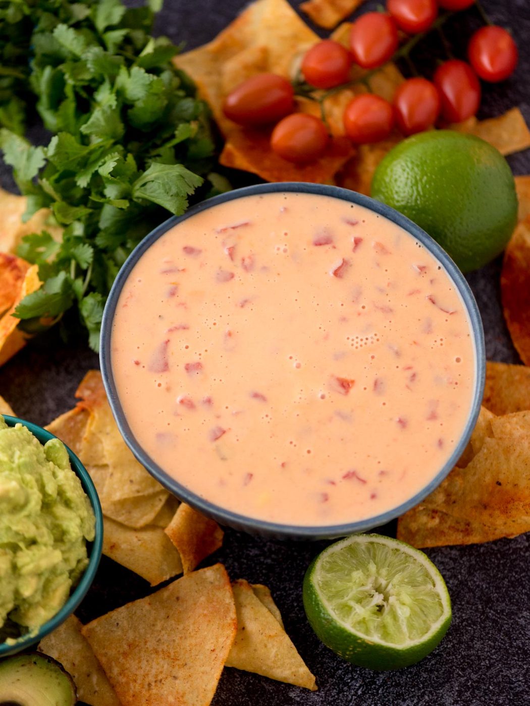 Large bowl of velveeta queso with lime wedge and tortilla chips around it.