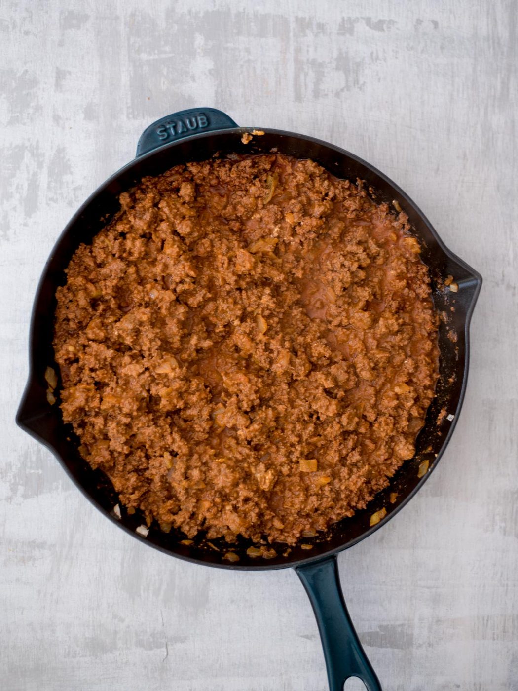 Cast iron pan filled with seasoned meat.