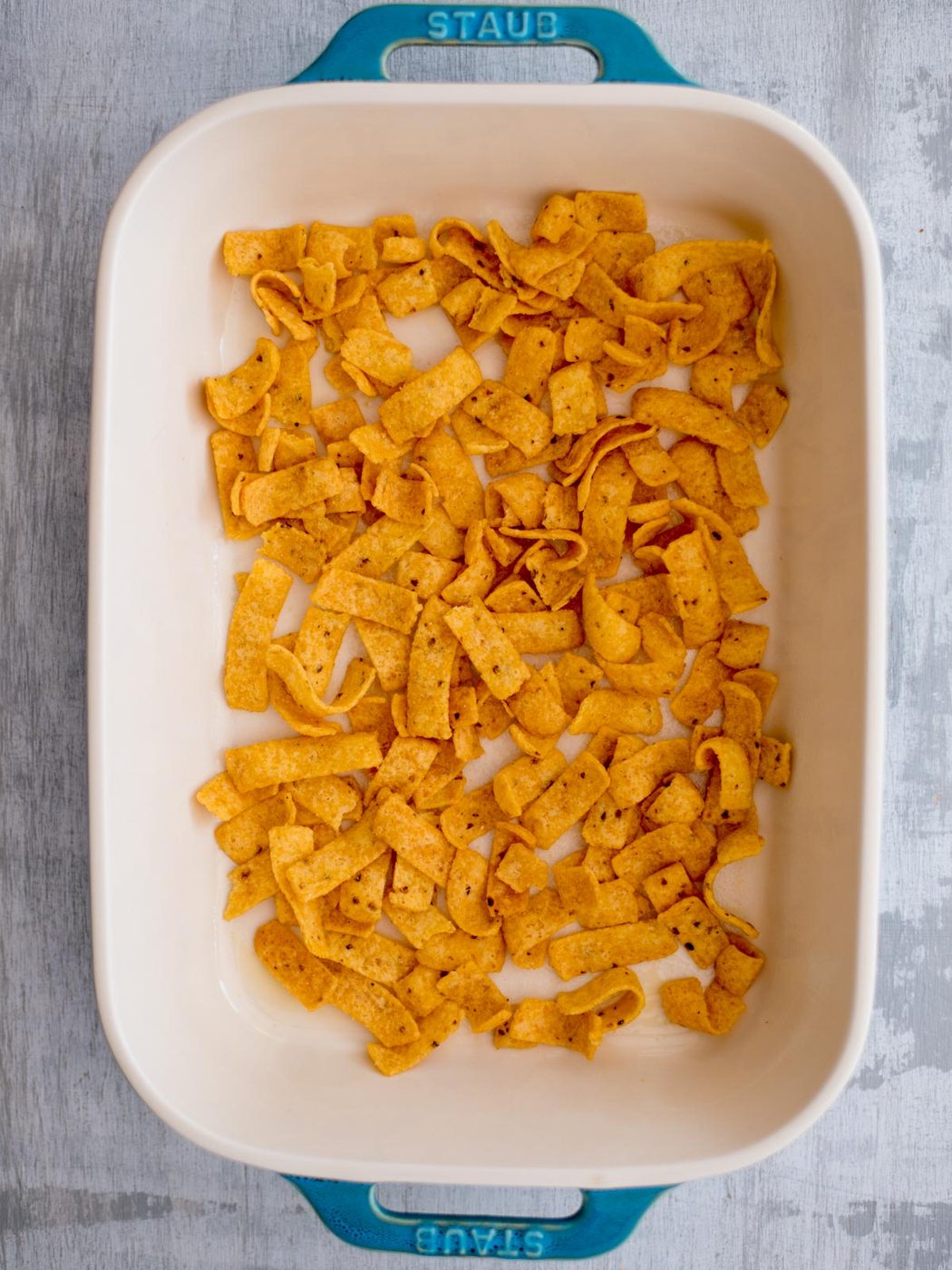 Casserole dish with frito chips spread over the bottom.