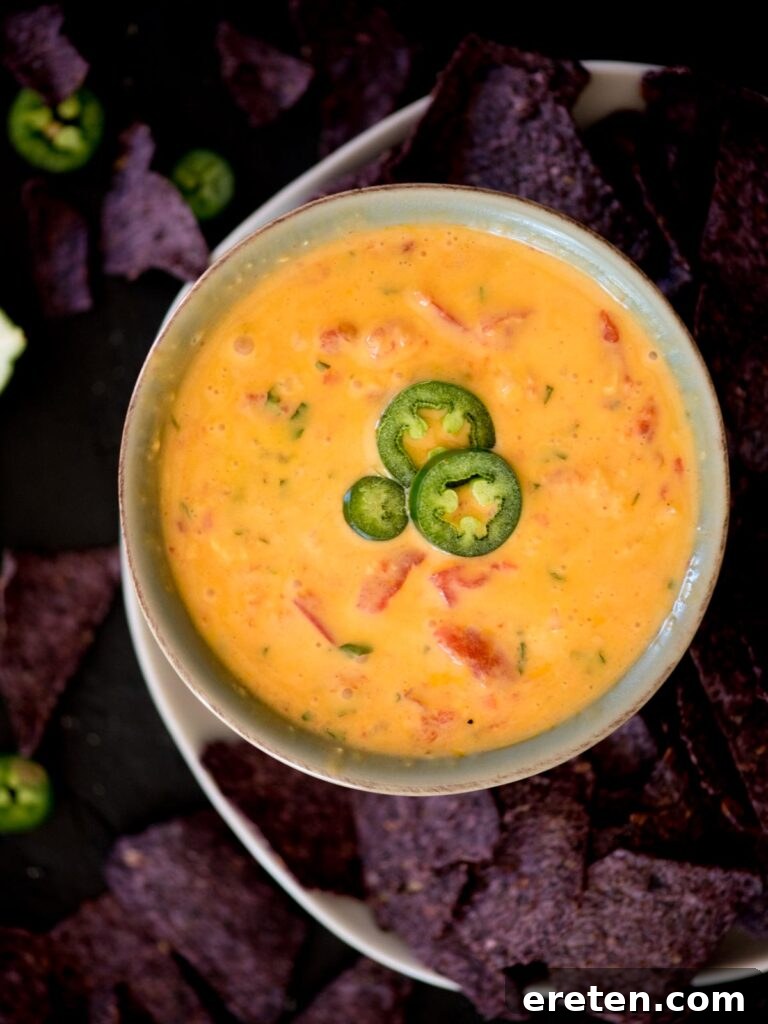 Ultimate Smoked Queso Dip 2 smoked queso dip in a bowl topped with jalapeno slices and surrounded by chips