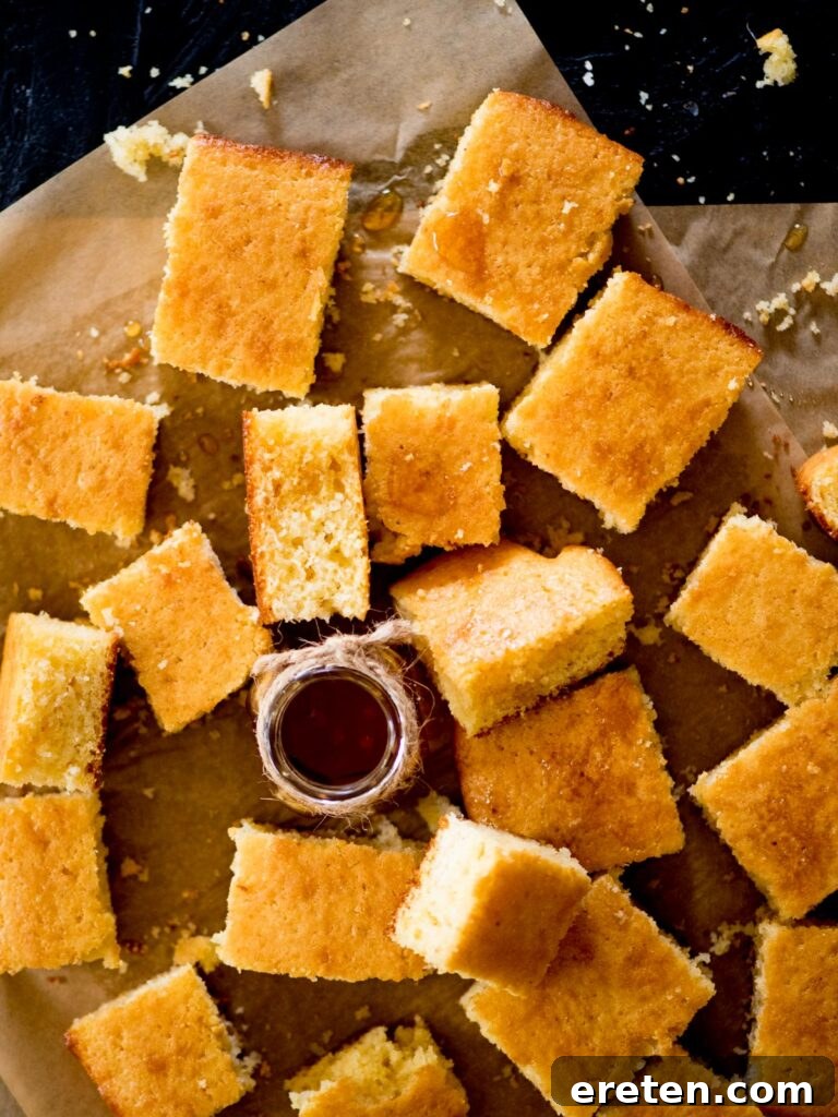 A slice of golden cornbread drizzled generously with honey, showcasing its moist interior