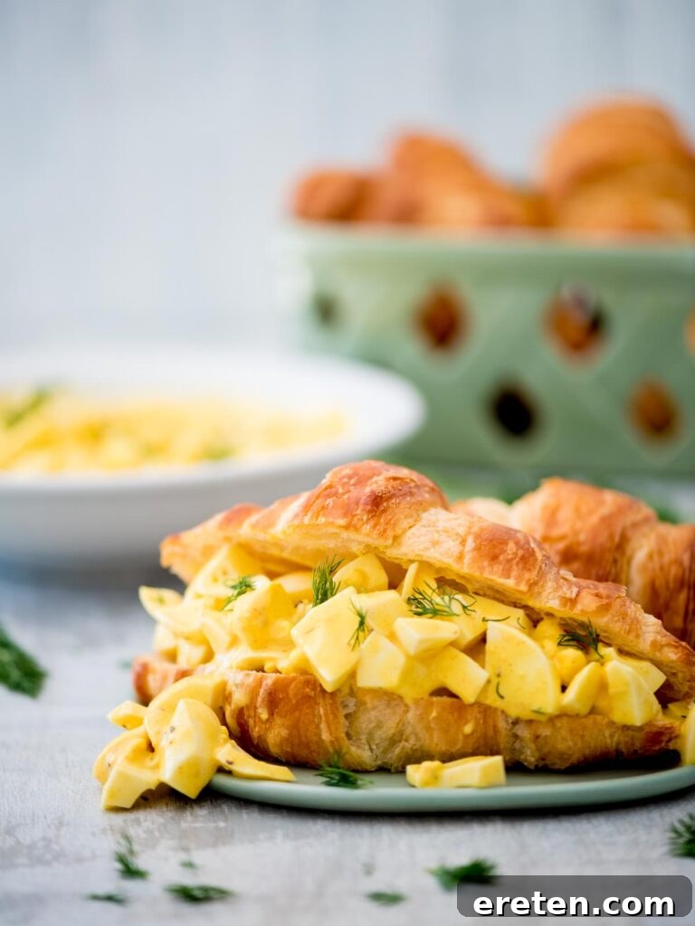 Dill-icious Egg Salad: Perfect for Quick Wraps and Elegant Tea Sandwiches 11 A beautifully presented classic egg salad sandwich on a flaky croissant with fresh dill garnish
