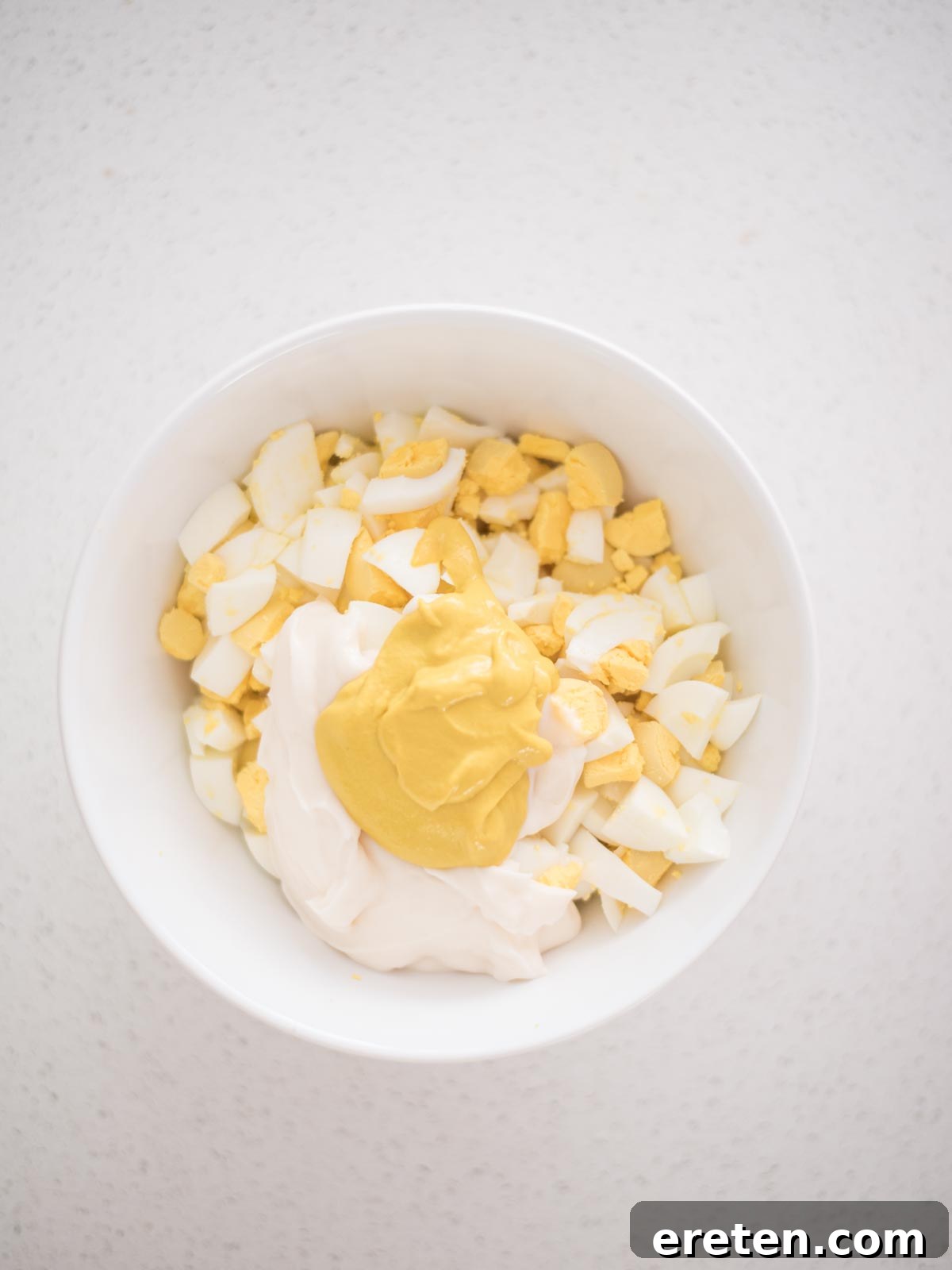 Dill-icious Egg Salad: Perfect for Quick Wraps and Elegant Tea Sandwiches 6 Mustard being added to the mayonnaise and eggs in a mixing bowl for the egg salad dressing