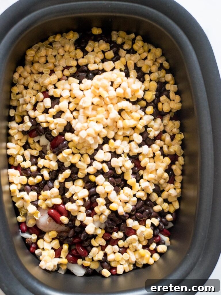 Sweet corn kernels are added to the slow cooker, providing a burst of color and sweetness to the chili ingredients.