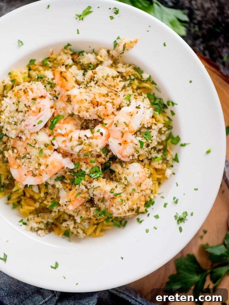 No-Fuss Baked Shrimp Scampi 2 baked shrimp scampi in a bowl on top of orzo pasta and sprinkled with parsley