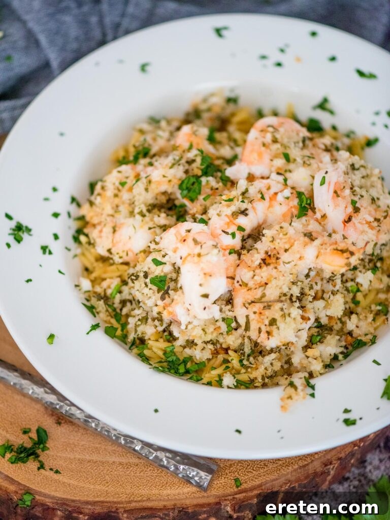 No-Fuss Baked Shrimp Scampi 9 baked shrimp scampi in a bowl on top of orzo pasta and sprinkled with parsley