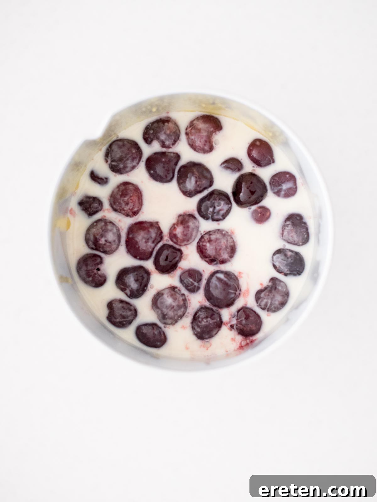 Frozen cherries being mixed into the ice cream base within the churner.