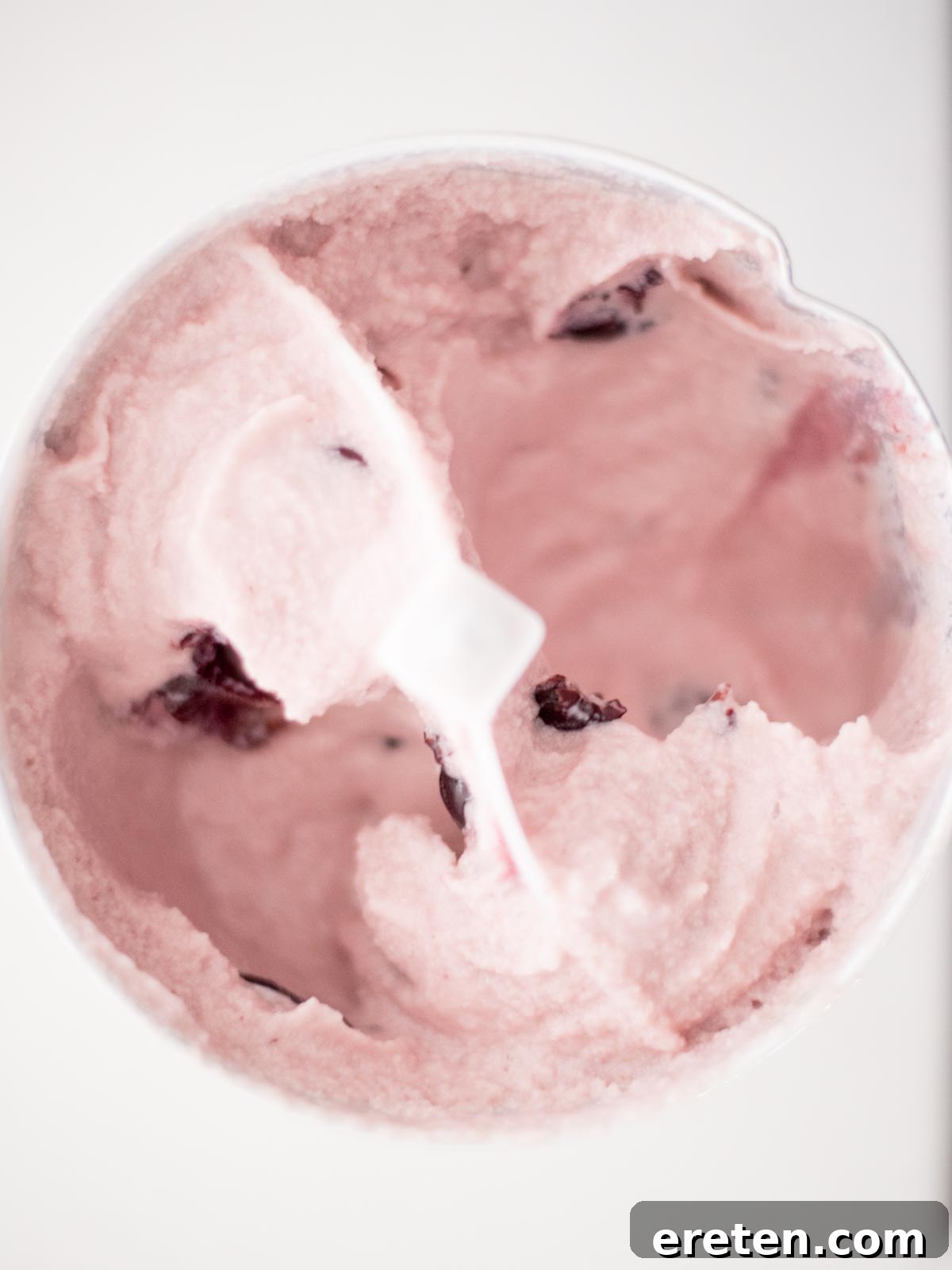 The homemade black cherry ice cream churning in an ice cream maker, nearing completion.