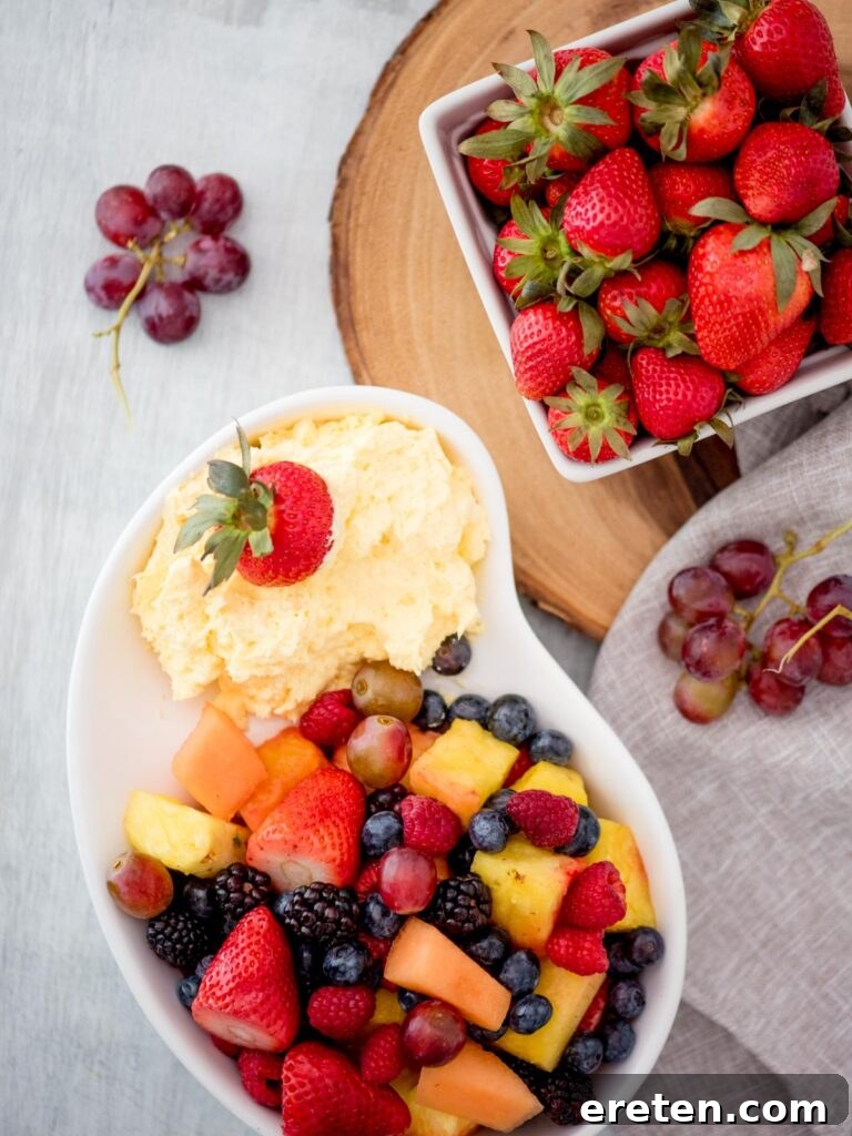 A beautifully presented bowl of creamy yogurt fruit dip, surrounded by an assortment of fresh fruits like strawberries, blueberries, and apple slices, inviting guests to indulge in a healthy and delicious snack.