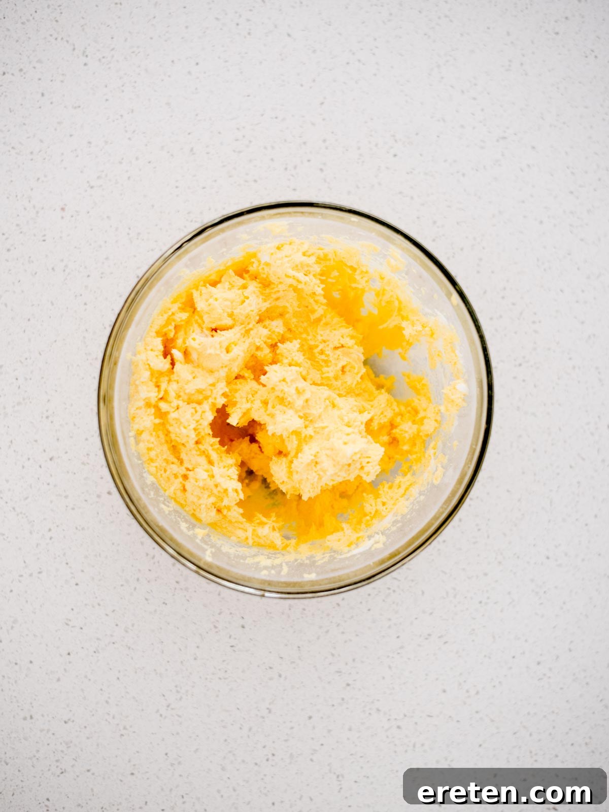 The yogurt fruit dip, a creamy and fluffy mixture, is shown thoroughly combined in a large mixing bowl after being whipped with an electric mixer, exhibiting its smooth, ready-to-serve texture.