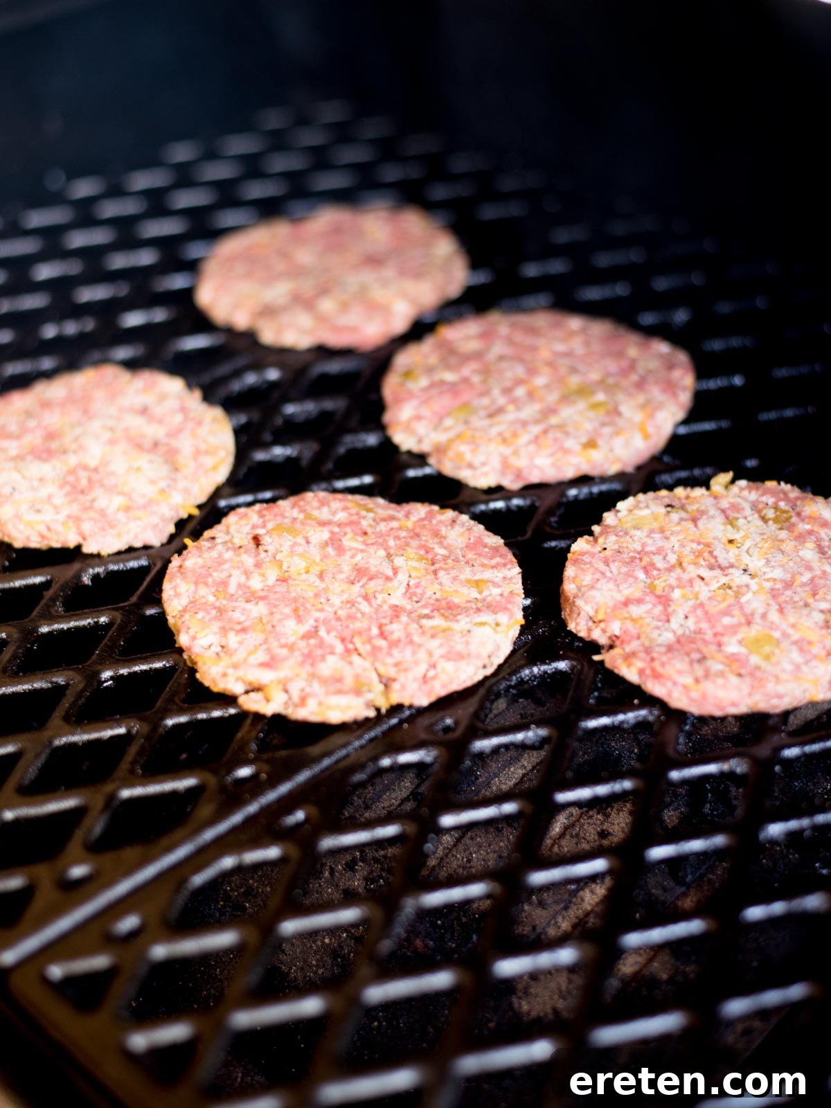 raw burgers on an electric smoker grate