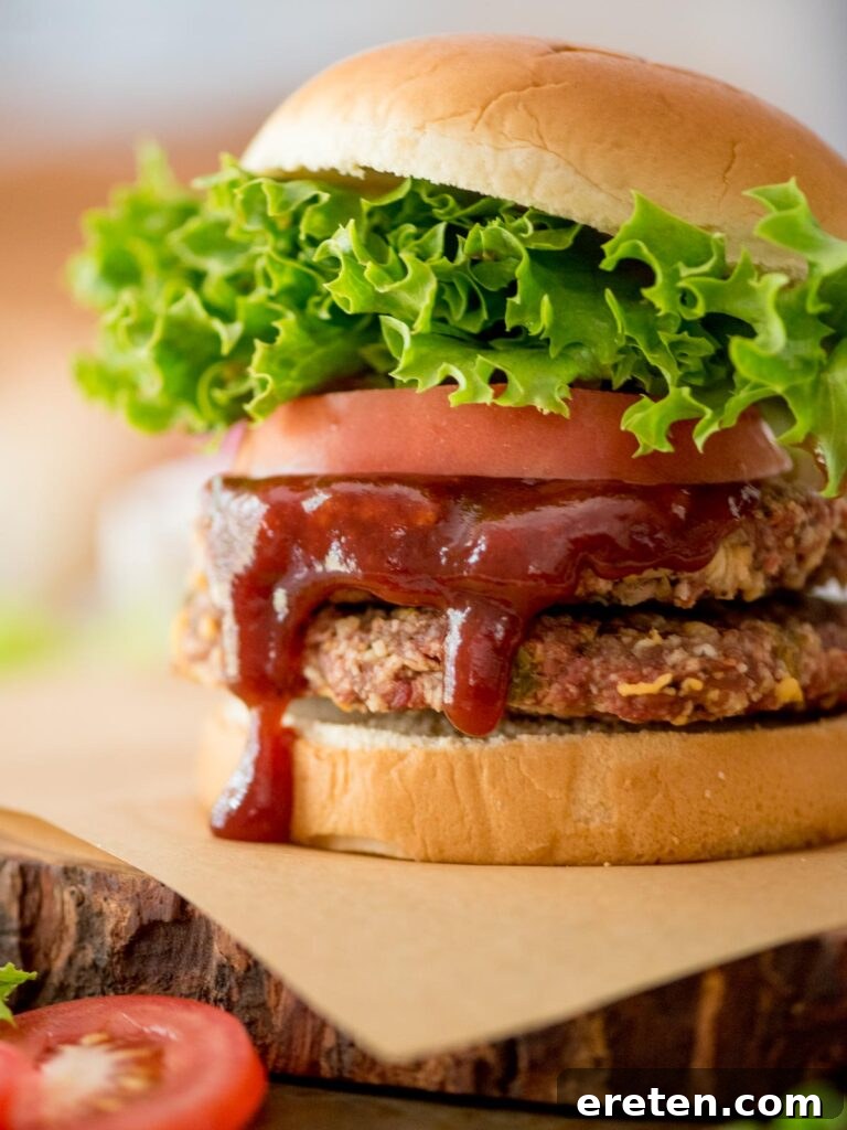 smoked burger on a bun topped with lettuce, tomatoes, and bbq sauce