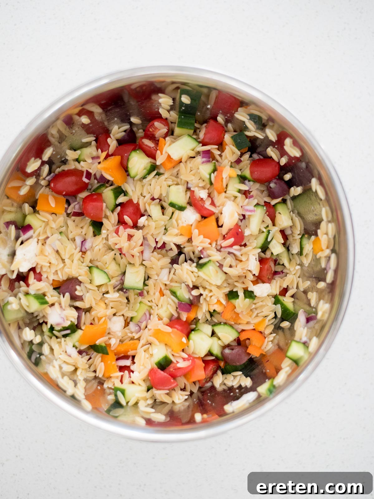 vegetables combined with cooked orzo in a large mixing bowl