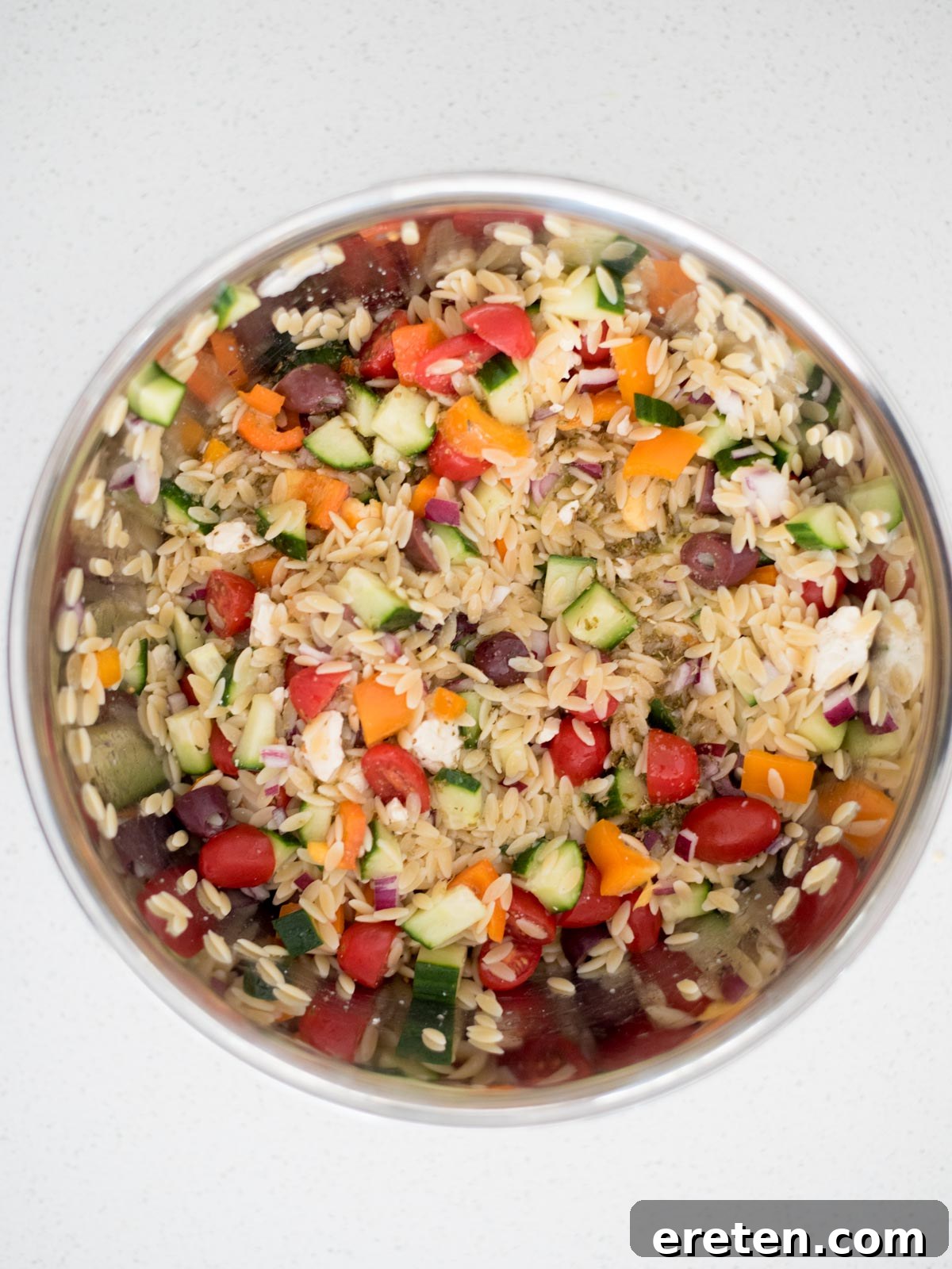dressing added to the mixing bowl with the vegetables and orzo