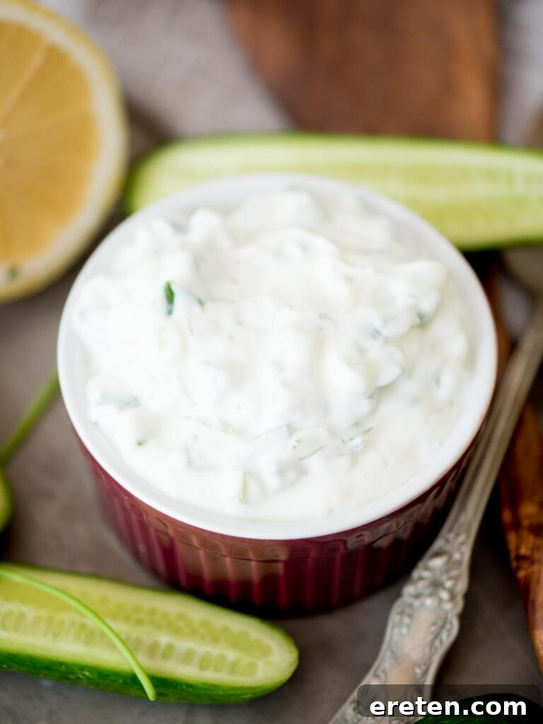 tzatziki sauce in a bowl surrounded by cucumbers and lemons