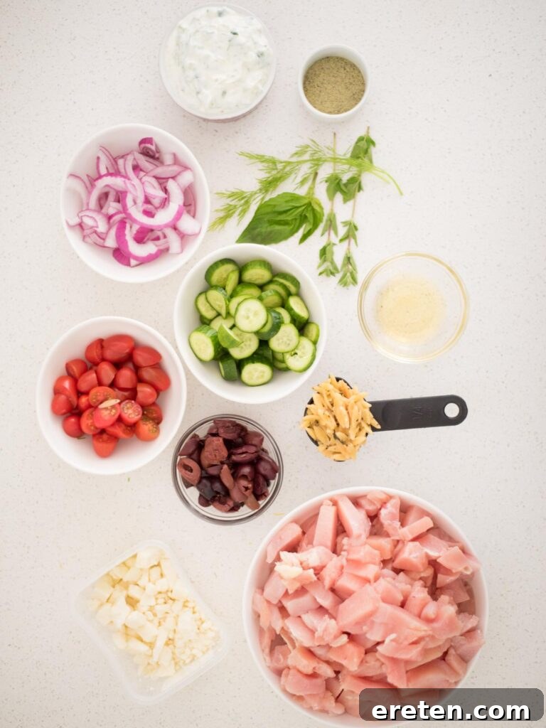 Assortment of fresh ingredients for Greek Chicken Bowls including vegetables, feta, and seasoning