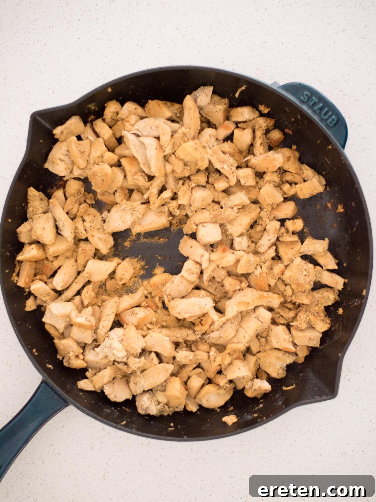 Chicken cooking in a skillet, seasoned with Greek spices