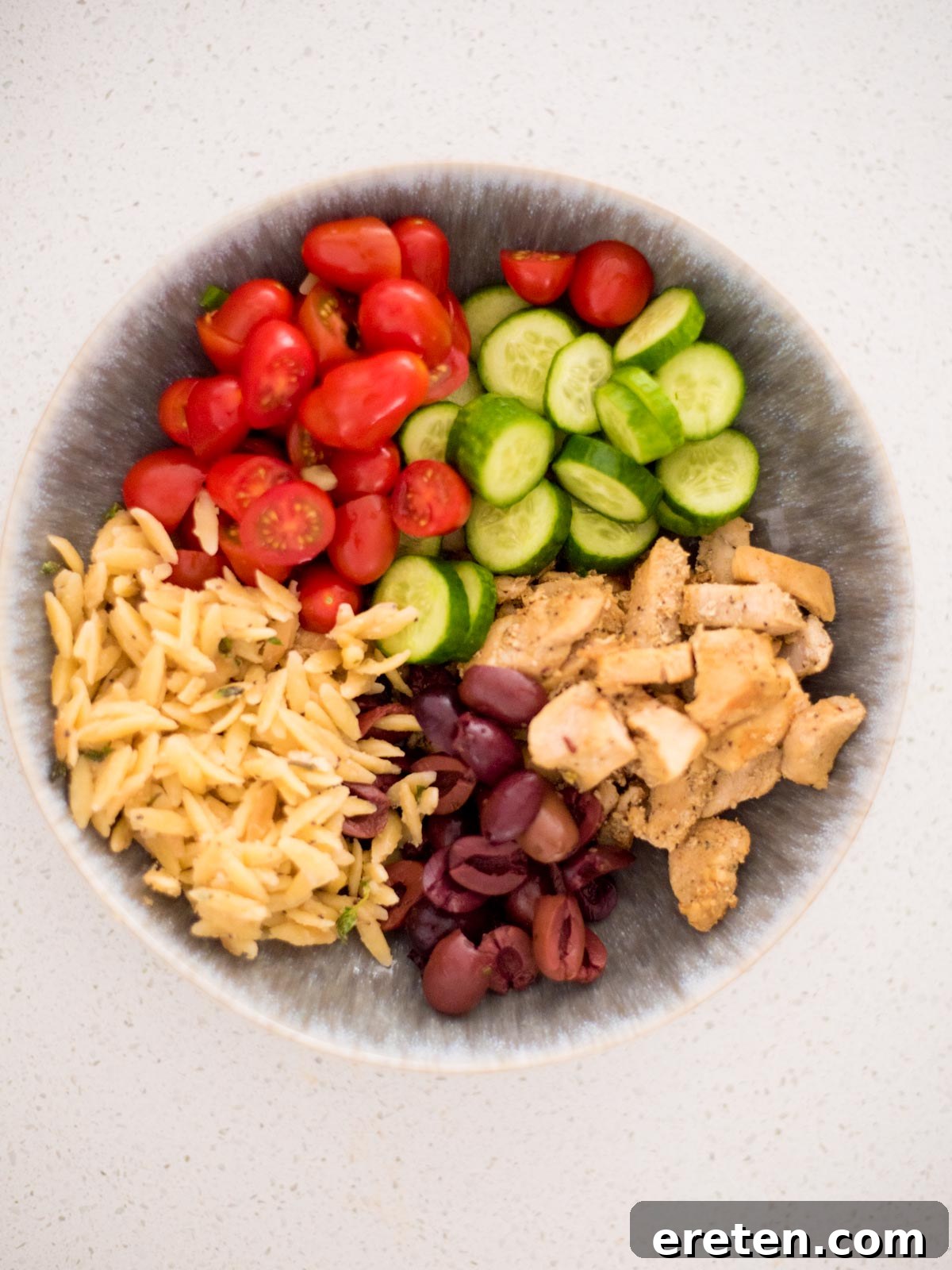 Assembly of a Greek Chicken Bowl, showing ingredients arranged before adding tzatziki