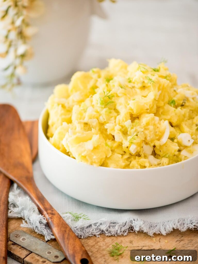 potato salad topped with fresh dill in a white bowl