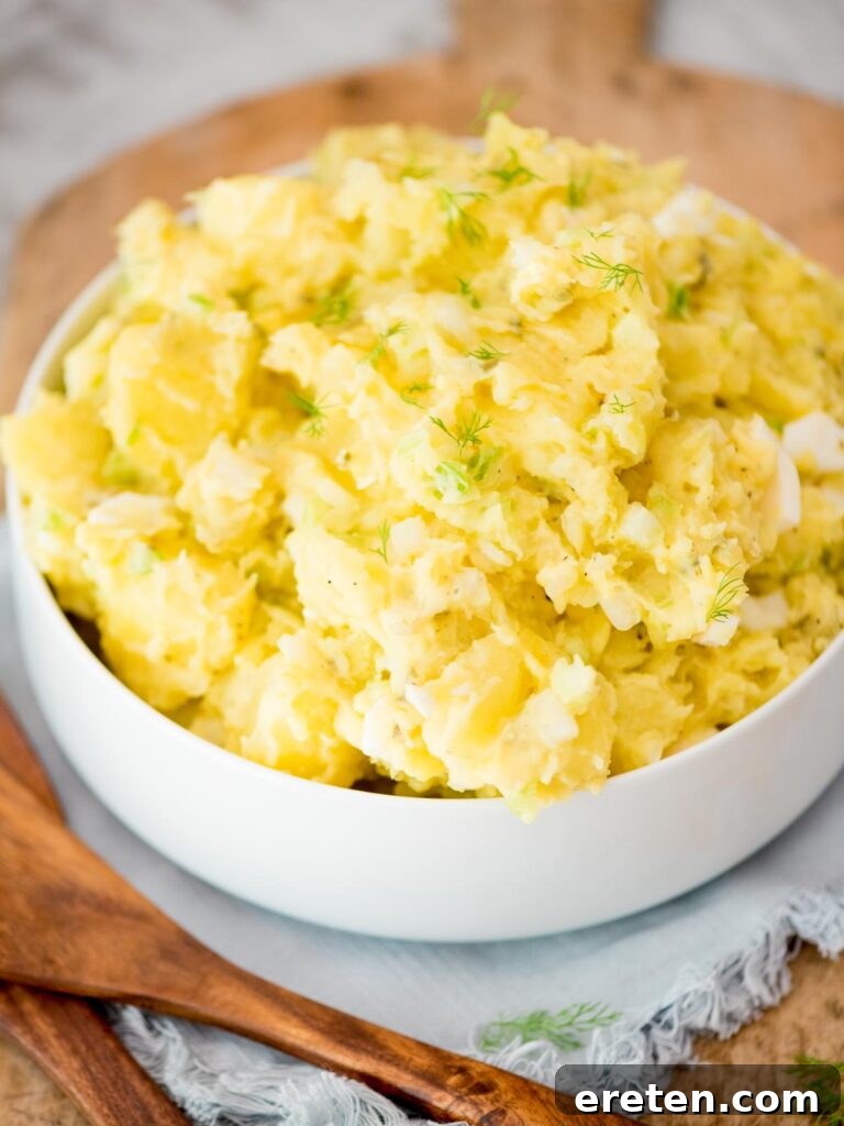 potato salad topped with fresh dill in a white bowl
