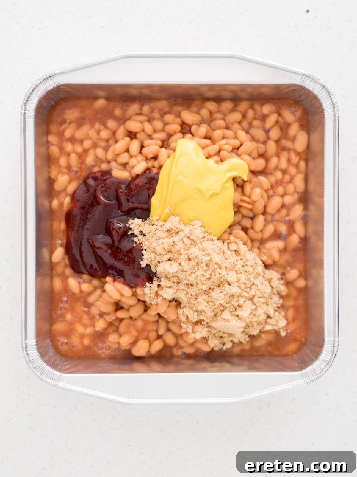 All the ingredients for smoked baked beans mixed together in a disposable aluminum pan, ready for the smoker.