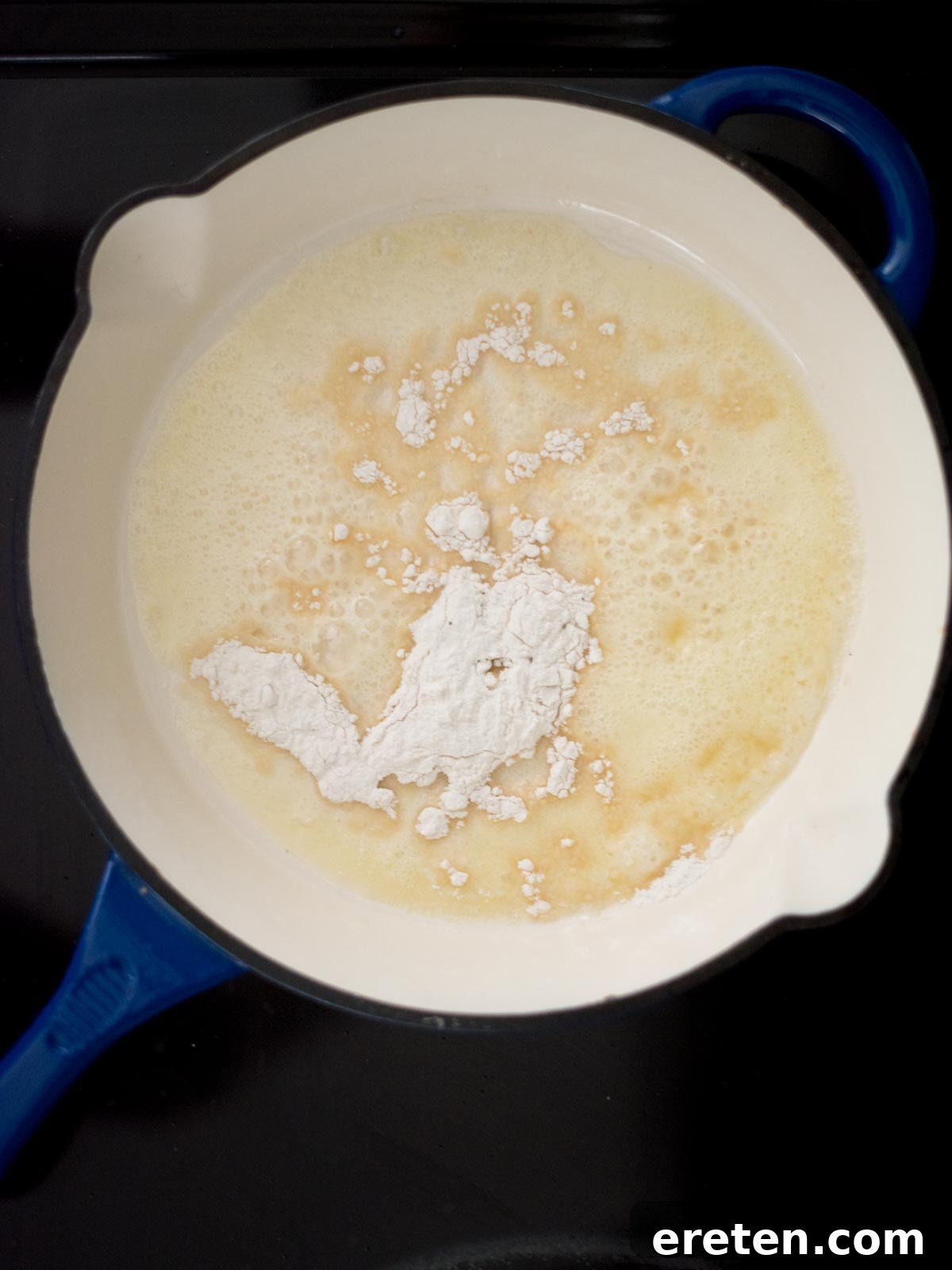 Hearty Southern Brown Gravy 5 All-purpose flour being added to melted butter in a hot skillet on the stove, beginning the roux formation.
