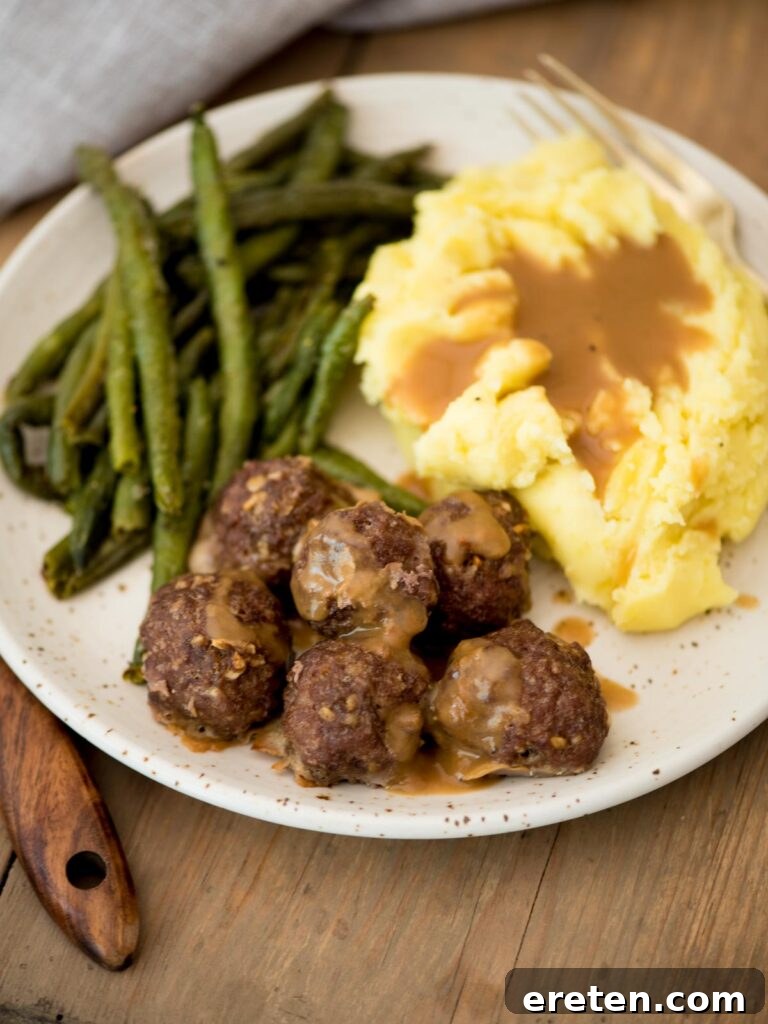french onion meatballs served on a plate with creamy mashed potatoes, rich brown gravy, and crisp roasted green beans