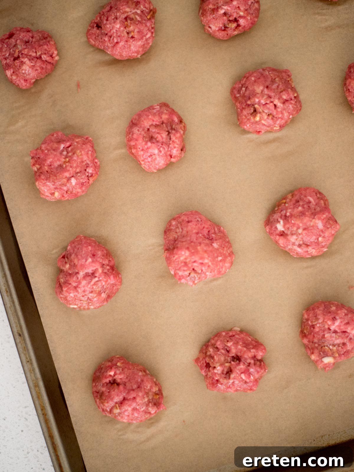 meatballs carefully formed into smooth, round balls and arranged on a parchment-lined baking sheet, ready for baking