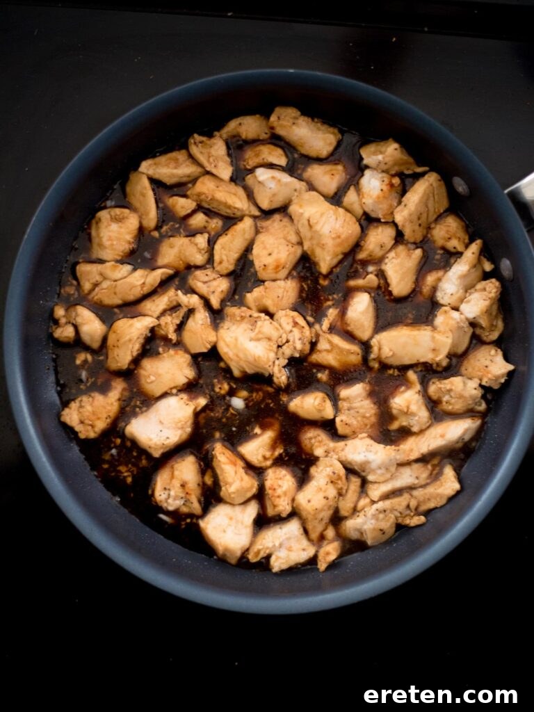 Golden-brown chicken breast chunks reintroduced to a frying pan and coated with the rich General Tso sauce.