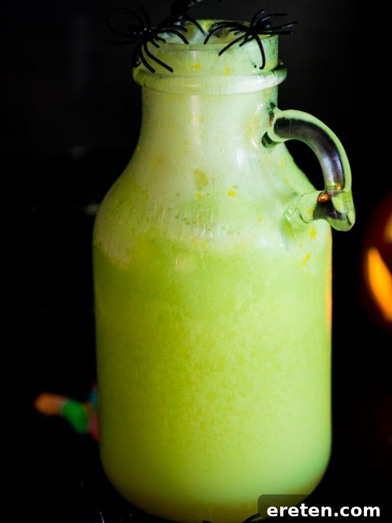 A large pitcher filled with vibrant green Bug Juice, topped with a frothy layer from the melted lime sherbet, ready to be served.