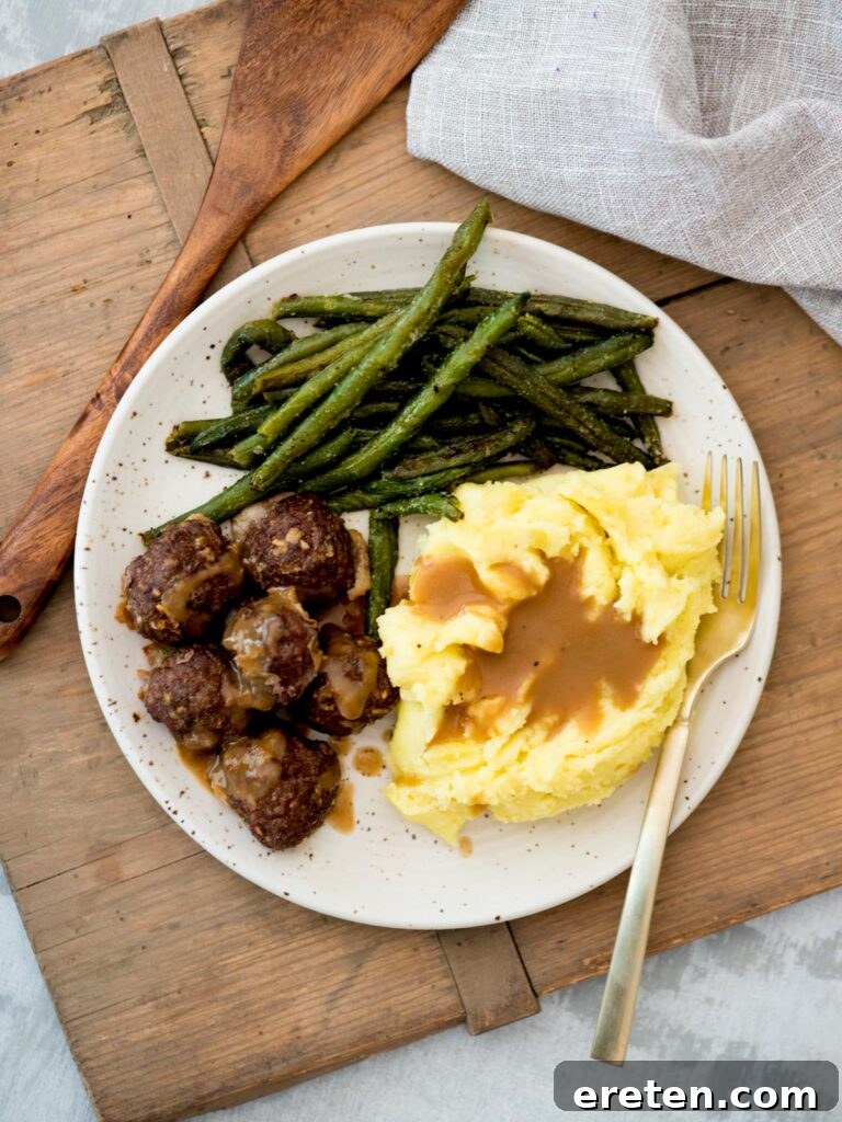 Top view of mashed potatoes and gravy, green beans and french onion meatballs.
