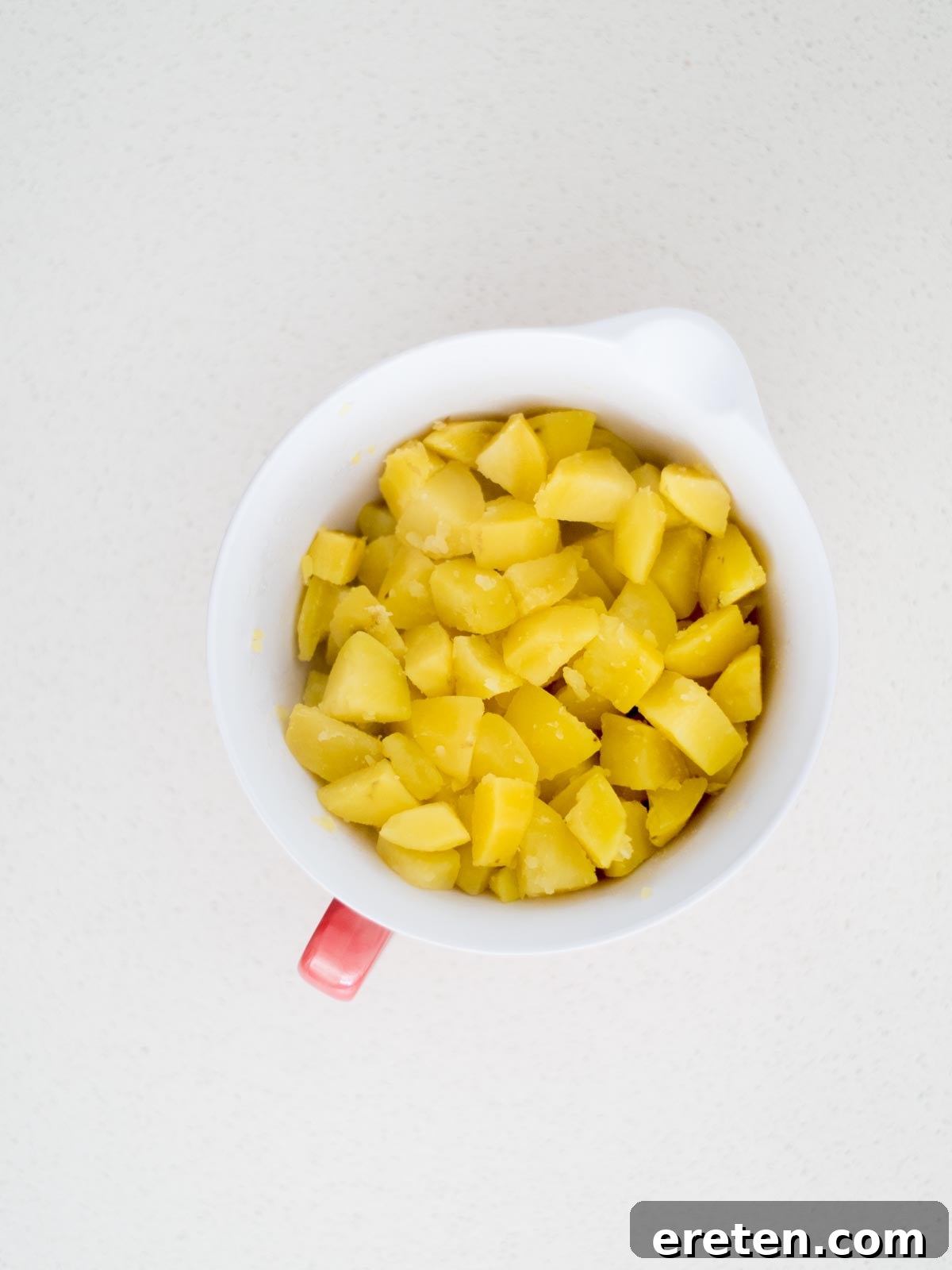 Mixing bowl with cooked cut up potato pieces.